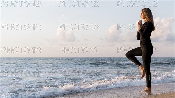 Woman meditating beach with copy space