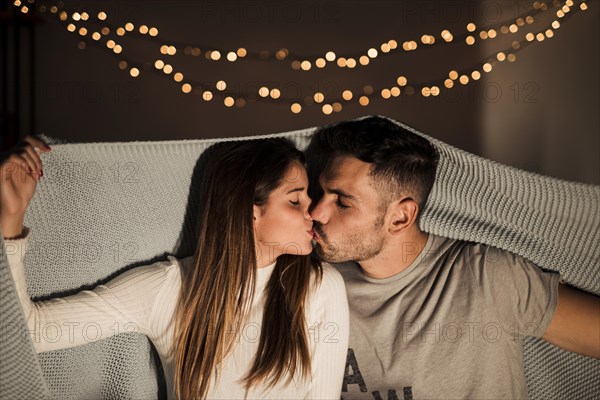 Young woman kissing with man coverlet