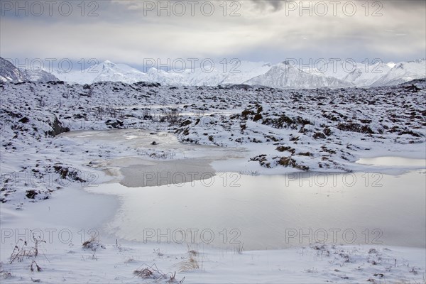 Frozen pond and snow covered mountains in winter