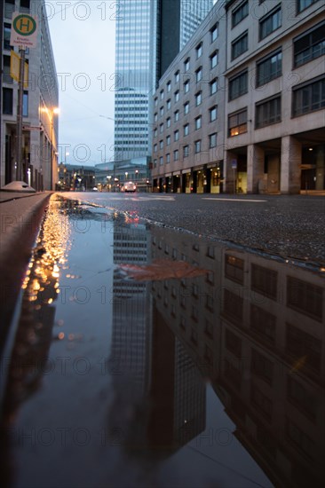 Reflection in a puddle between skyscrapers. Cityscape with modern office buildings and streets. Insurance companies and banks as a cityscape in Frankfurt am Main