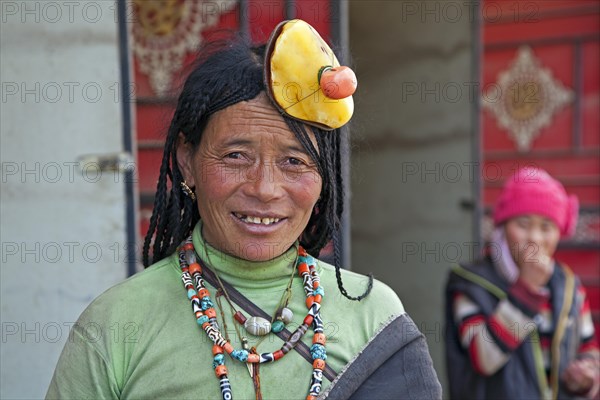 Portrait of Tibetan Khampa woman wearing traditional amber and red coral hair piece at Zhuqing