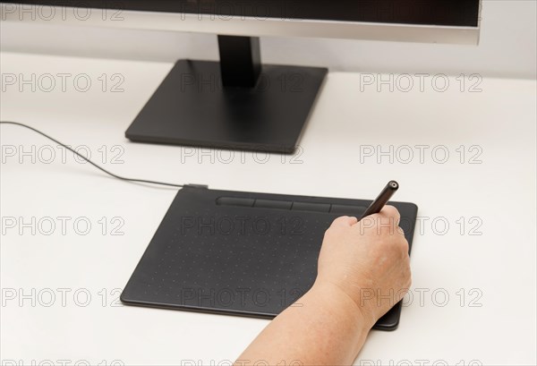 Woman hand working on her computer with a digital graphic tablet
