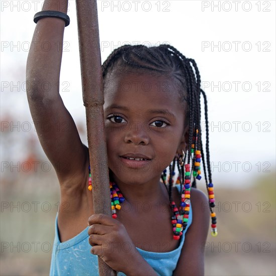 Little Creole girl with braided hair decorated with colourful beads in the village Rebelados on the island Santiago