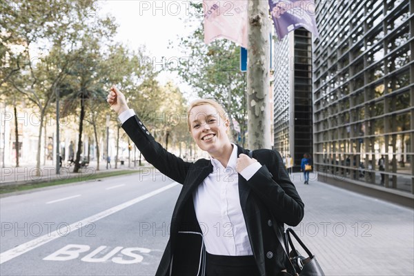 Cheerful executive formal wear catching taxi street