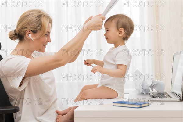 Mid shot mother playing peek boo with baby