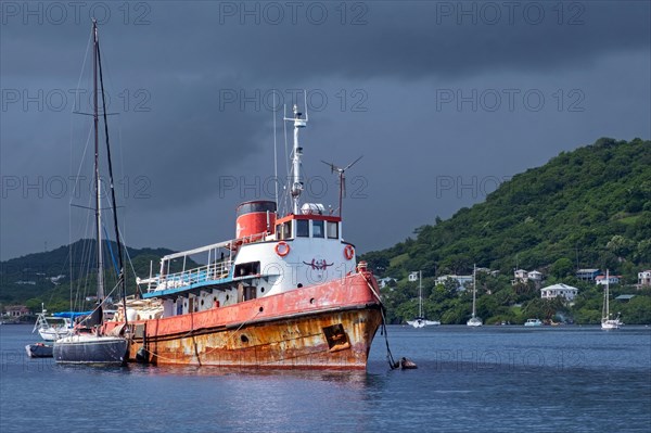 Old rusty ship among sailing boats waiting out the end of hurricane season in Woburn Bay