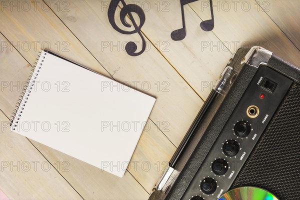 Overhead view spiral notepad musical note amplifier wooden desk