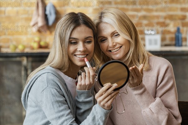 Women home putting lipstick together