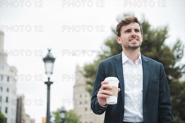 Portrait smiling young businessman holding takeaway coffee cup hand