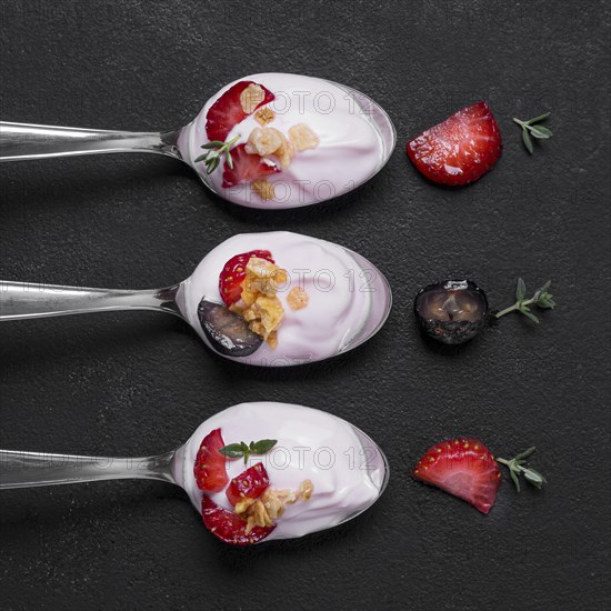 Top view collection spoons with yogurt fruits