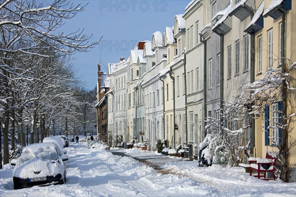 Historic houses and snow covered cars in street in Luebeck