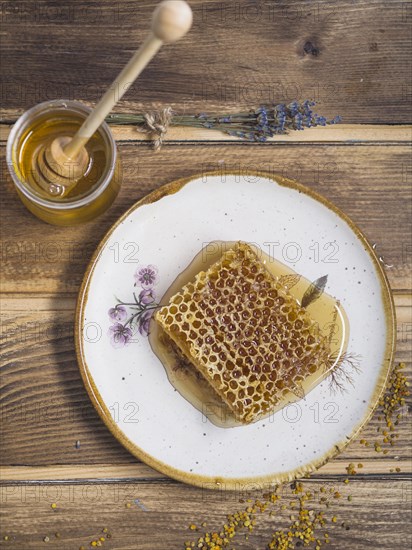 Lavender honey pot with wooden honey dipper bee pollens wooden table