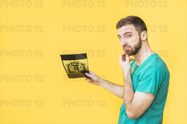 Thoughtful dentist holding teeth x ray