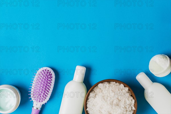 Cosmetics bottles cream hairbrush salt blue backdrop