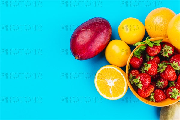 Mango oranges bowl strawberries blue background