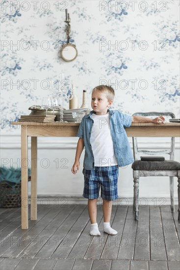 Portrait boy standing near table living room