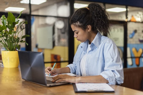 Side view woman office working with laptop