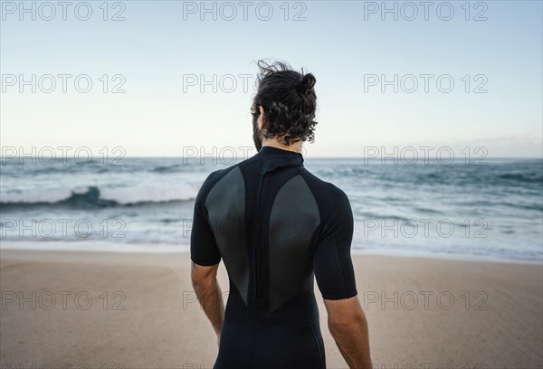 Surfer walking alongside ocean from shot