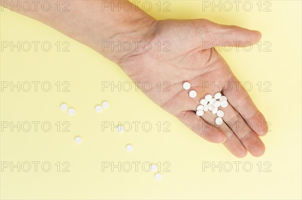 White round tablets hand person against yellow background