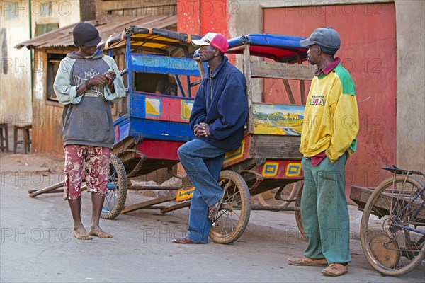 Three pousse-pousse drivers waiting for customers in the streets of the city Ambalavao