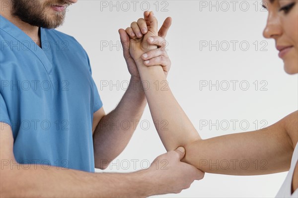 Side view male osteopathic therapist checking female patient s elbow joint