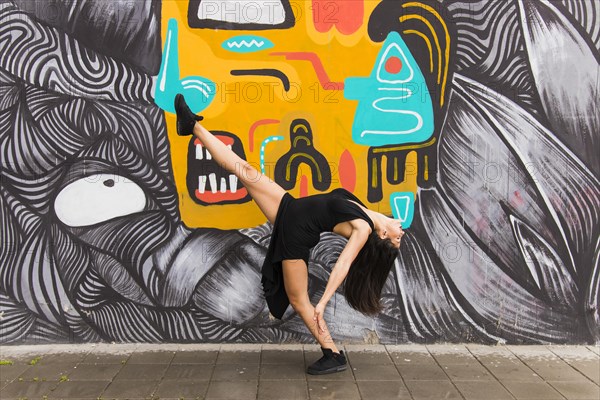 Tango female dancer posing against creative graffiti wall