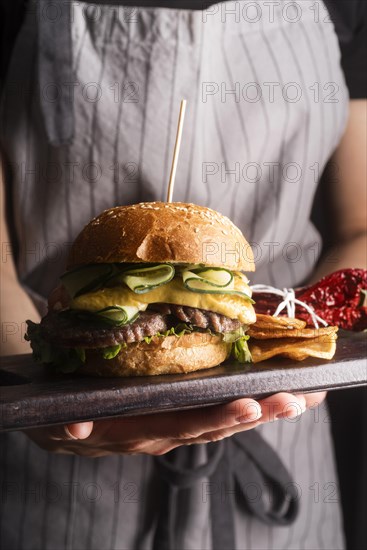 Woman holding tasty meal with hamburger