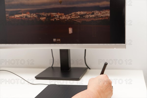 Woman hand working on her computer with a digital graphic tablet