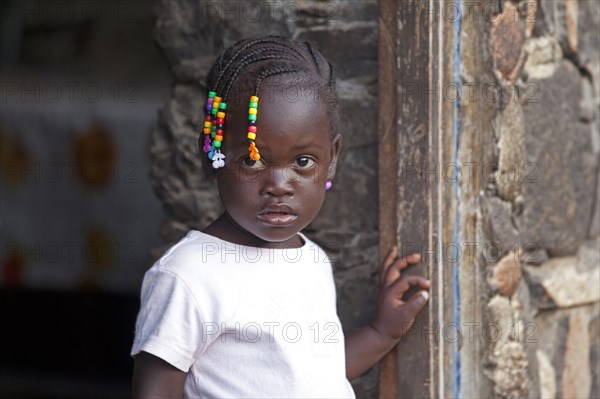 Little Creole girl with braided hair decorated with colourful beads in the village Rebelados on the island Santiago