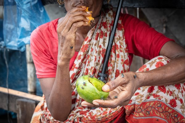 Woman eating a mango in front of her house