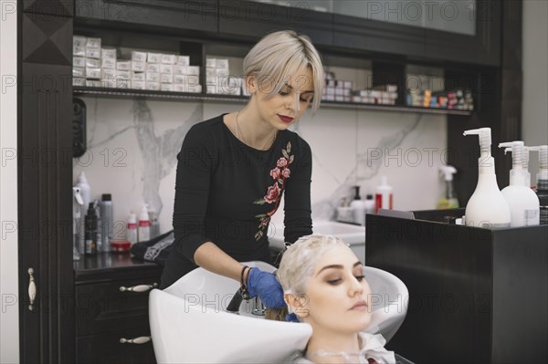 Professional stylist washing hair customer