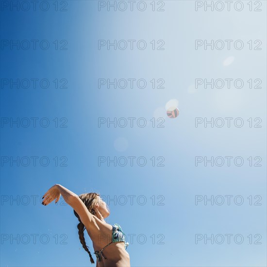 Woman playing beach volley with sun background