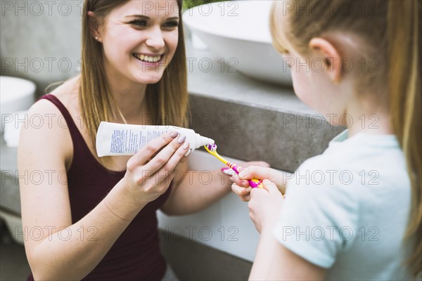 Charming woman helping daughter with toothpaste