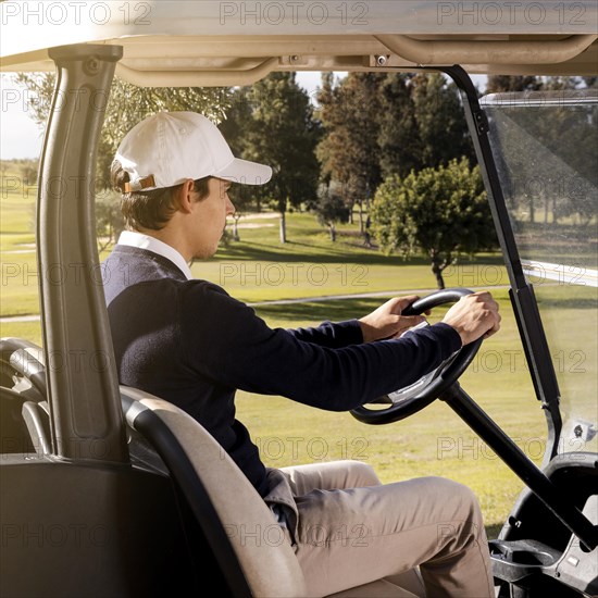 Side view man driving golf cart field