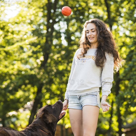 Young woman throwing ball her dog park