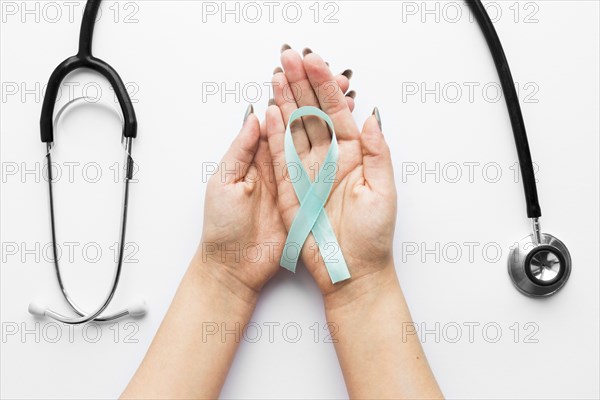 Hands with light blue ribbon near stethoscope