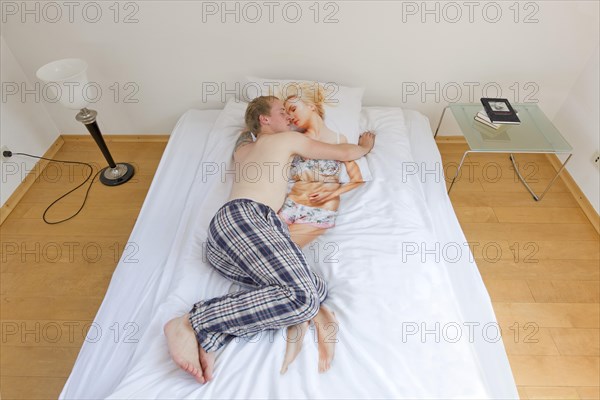 Man sleeping in bed and turning round a duvet cover with the depiction of a young woman