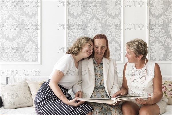 Granddaughter hugging granny looking album home