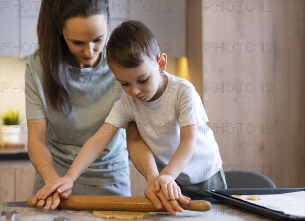 Medium shot kid woman using rolling pin