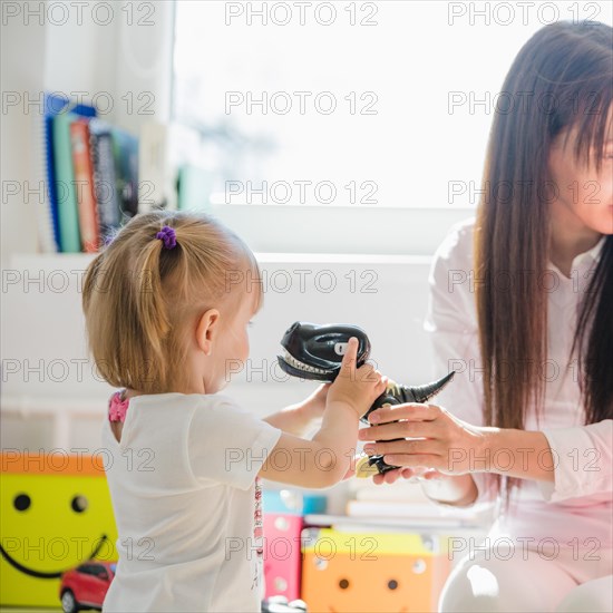 Woman giving dinosaur girl looking away