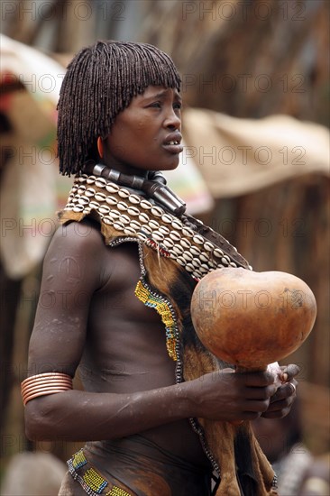 Portrait of woman of the Hamar tribe with calabash in traditional dress