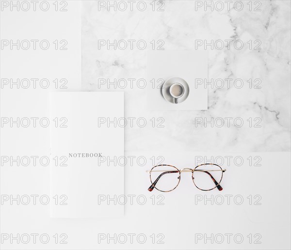 Notebook text paper coffee cup eyeglasses white texture backdrop