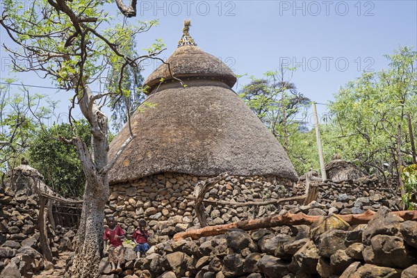 Two black children in front of traditional stone hut with thatched roof of the Konso