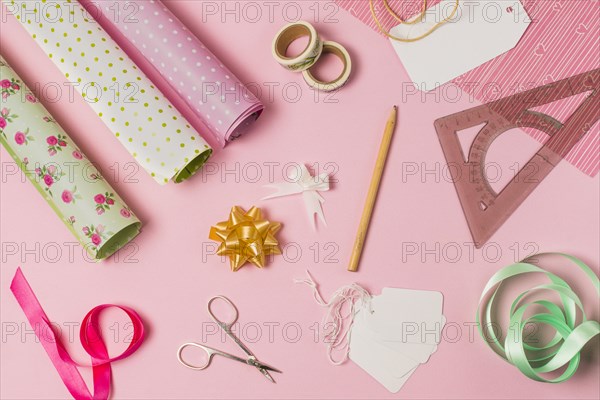 High angle view stationery supplies with gift wrap tags pink background