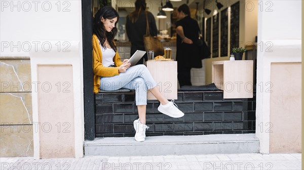 Woman sitting cafe table with tablet