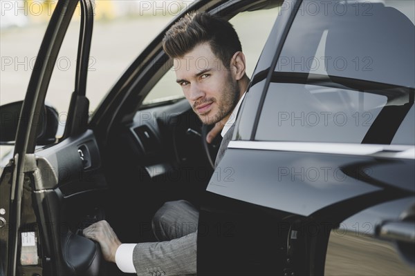 Young businessman opening car door