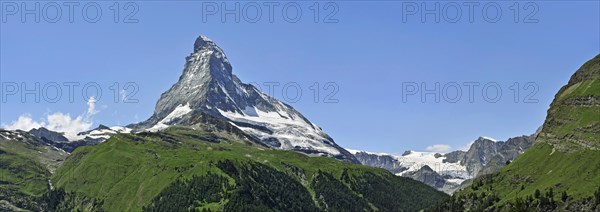 Panoramic view over the Matterhorn mountain with alpine meadows and pine forests in the Swiss Alps