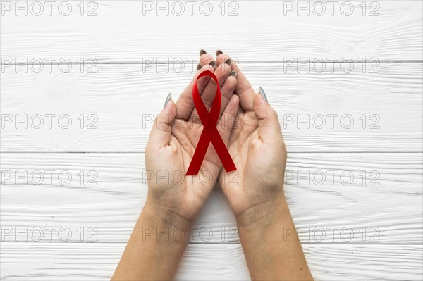 Hands with burgundy ribbon wooden background