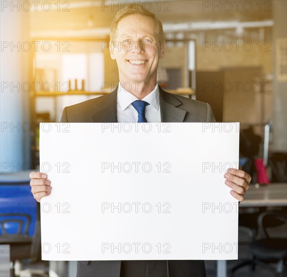 Portrait smiling mature businessman holding blank placard