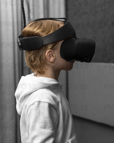 Side view young boy using virtual reality headset